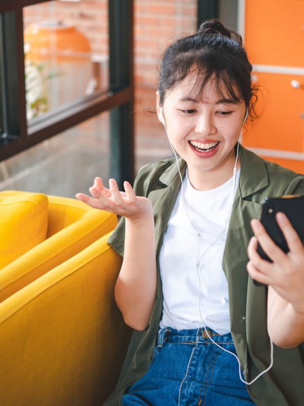 smiling-young-asian-woman-using-mobile-phone-checking-social-media-1.jpg